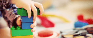 A child's hands play with Lego blocks
