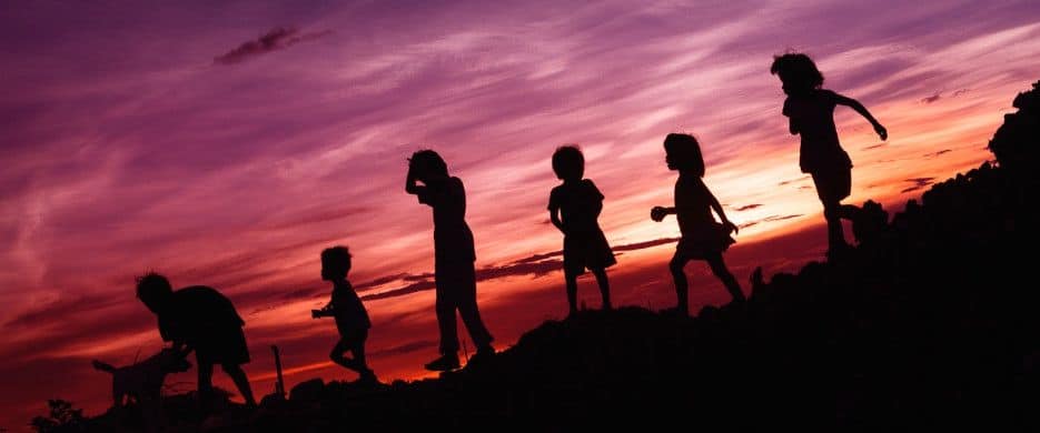 A row children in silhouette background red setting sun sky